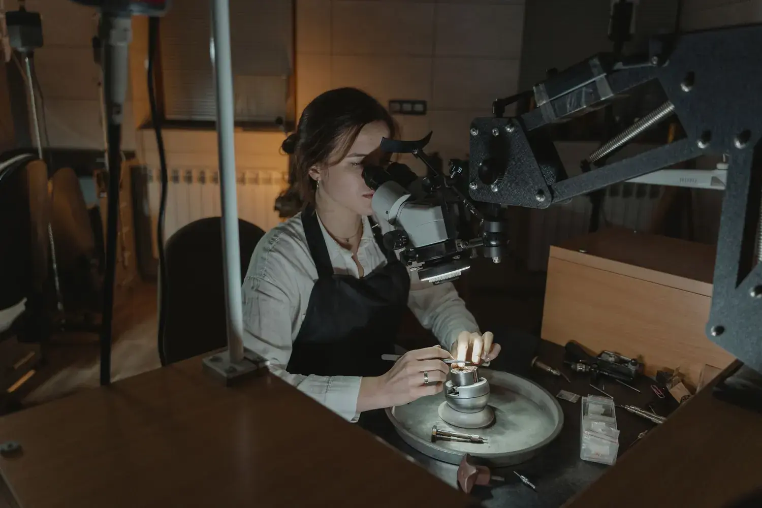 A jeweller working at the bench under a steady light.